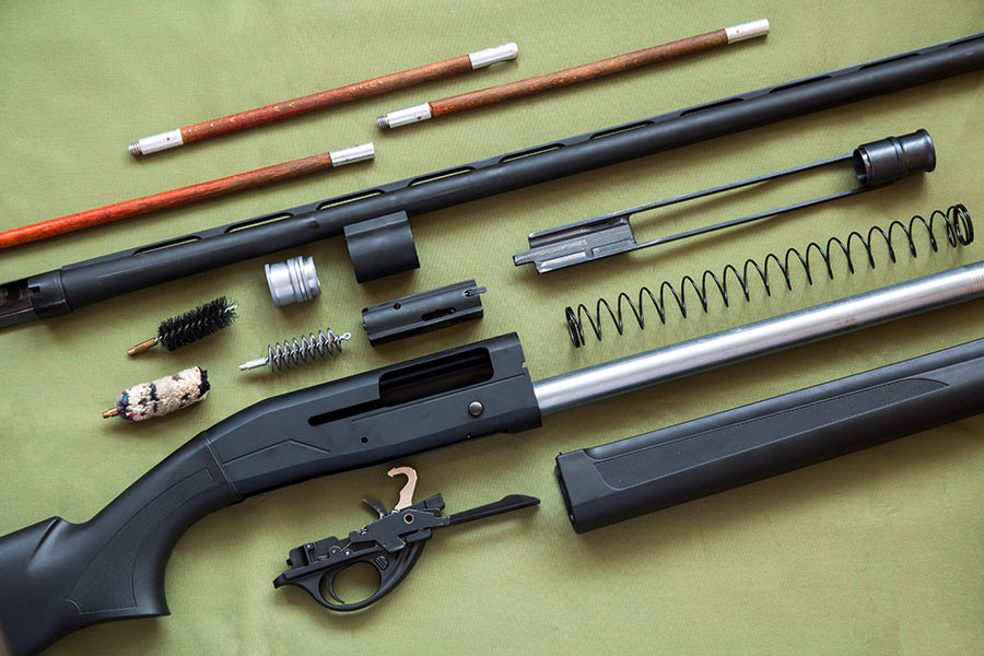 Disassembled shotgun on a surface, with gun cleaning supplies