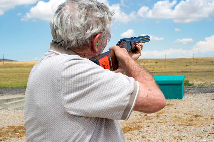 Shooter holding a shotgun, shooting at clay pigeons at Lee Kay Public Shooting Range