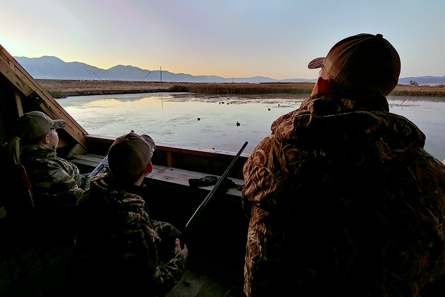 Young waterfowl hunters sitting in a duck blind above a marsh near the Cache Valley Public Shooting Range
