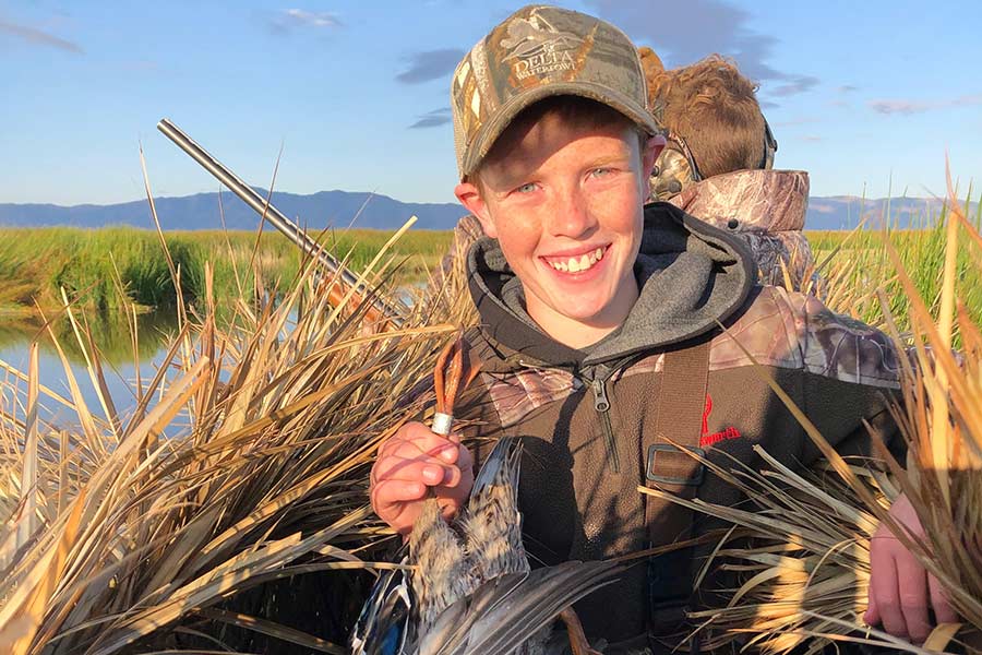 Young hunter holding a harvested duck with a band around its leg