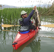 Man holding channel catfish from a kayak at Utah Lake
