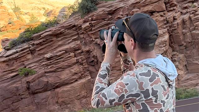 Wildlife photographer and videographer Phil Tuttle holding a camera up at the mountains of Southern Utah