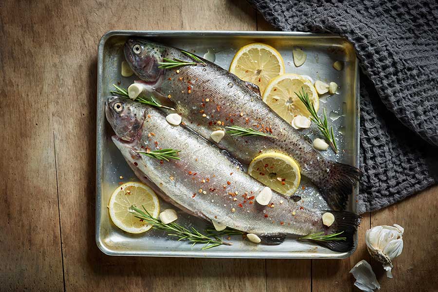 Fish in baking pan, with lettuce and lemons