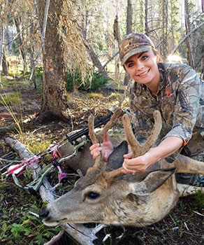 Woman with archery equipment and harvested buck deer