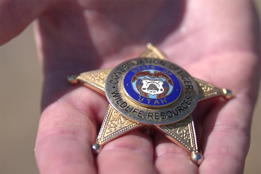 Hand holding Utah Division of Wildilfe Resources conservation officer badge